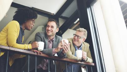 Three people talking on the balcony while drinking coffee