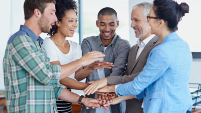 Work team in a circle using their hands to build a tower