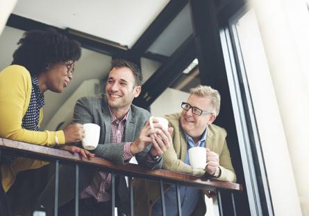 Three people talking on the balcony while drinking coffee