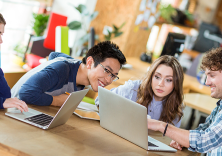 A group of people working together while on their laptops