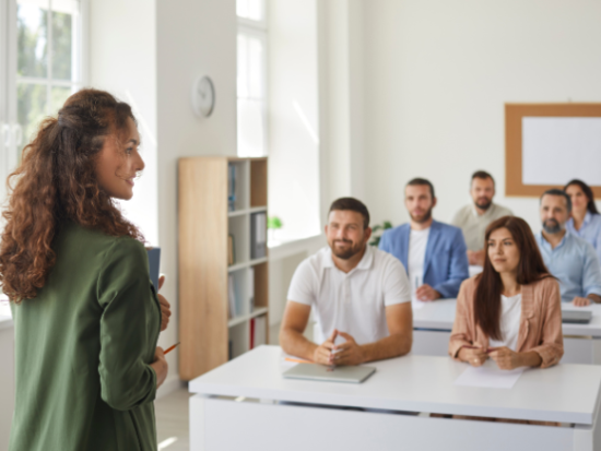 Woman teaching to class full of adult students