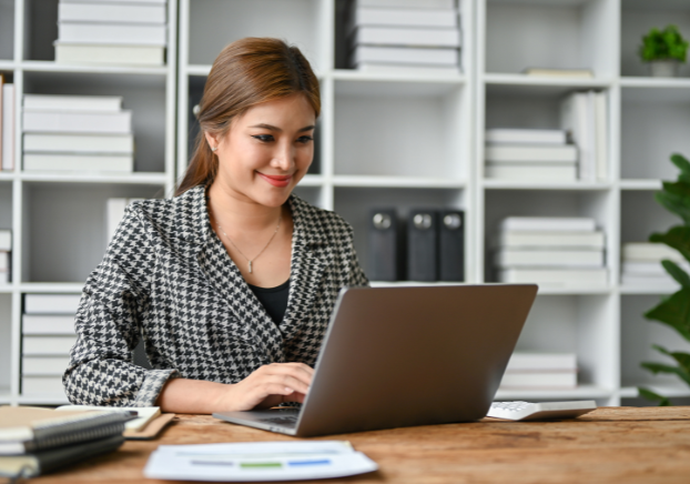 Young woman sitting at office desk working on laptop