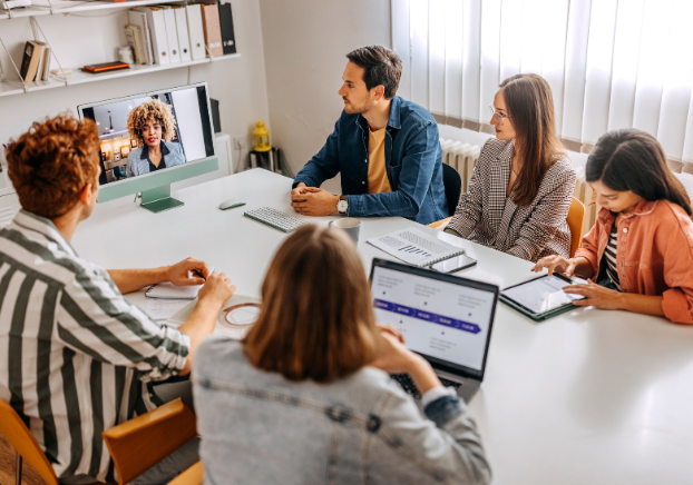 Group of professionals sitting at a table in a virtual meeting with a leader or colleague