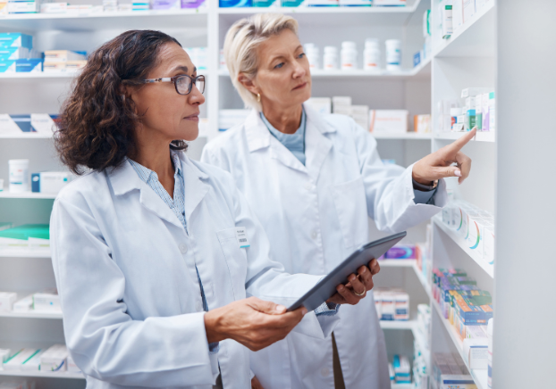 Two female pharmacy technicians discussing contents of pharmacy