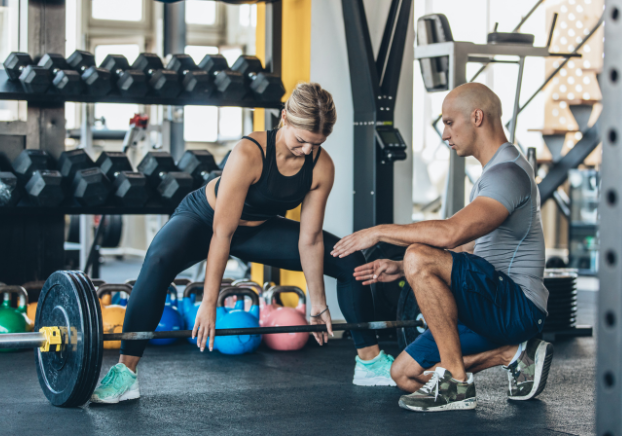 Professional trainer male helping female with exercise routine