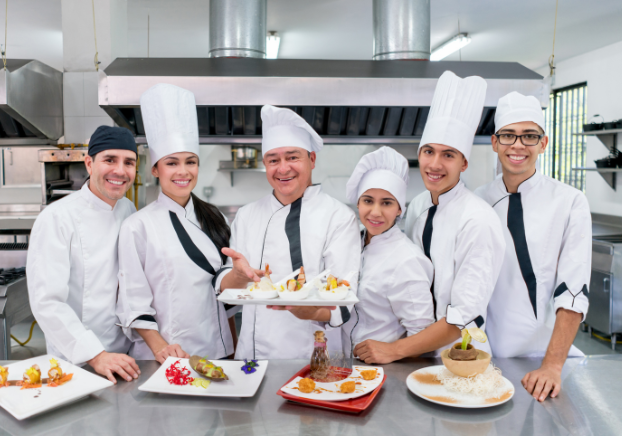Team of catering professionals in kitchen next to different foods