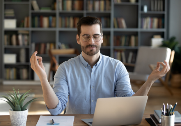 Male professional closing eyes and meditating at desk