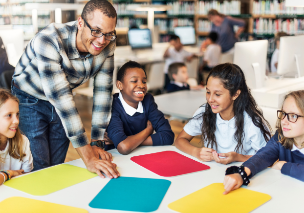 Male teacher's aide helping young elementary students